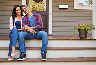 Couple sitting on the steps leading to a home.